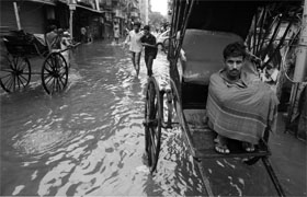 A hand rickshaw puller waits for passengers to ferry along the water-logged streets of Kolkata on Sunday. Heavy rain hit normal life as several parts of the city became waterlogged and train services were partially disrupted. 