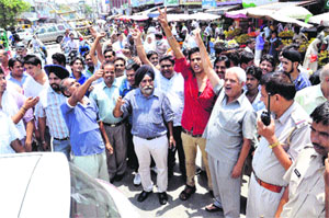 Shopkeepers block the old GT road opposite the bus stand in protest against power cuts in Karnal on Monday.