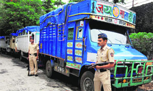 Policemen guard the trucks used to ferry 150 bags of cash and jewellery outside the income tax office in Mumbai on Tuesday.