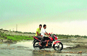 A motorcyclist with a pillion rider cross a rivulet near Bobiyan village in Kathua district.