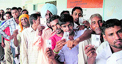 Voters show their voting cards for the panchayat elections at Chand Pur village near Jalandhar on Wednesday