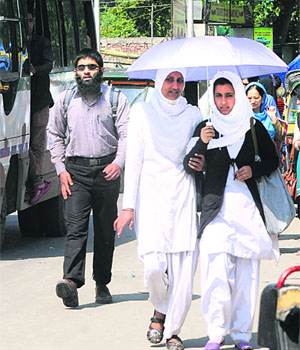 Students of Government Womens College protect themselves from the sweltering heat at Lal Chowk in Srinagar on Wednesday.