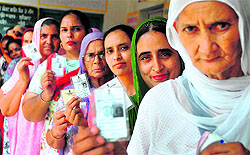 Women show their voter cards at a polling booth near Ludhiana on Wednesday
