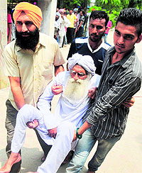 Tehal Singh (90), helped by his family members, on his way to a polling booth at Hambran village