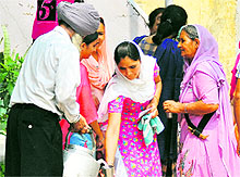 A man serves sweetened water at a polling booth near Ludhiana on Wednesday.