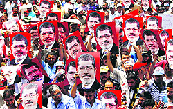 Supporters of Egyptian President Mohamed Mursi hold up his posters to show support to him in Cairo on Wednesday