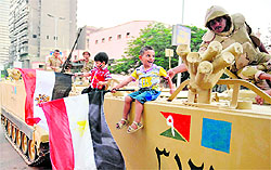 Egyptian children hold national flags as they pose for pictures on armoured personnel carriers in a Cairo street on Wednesday