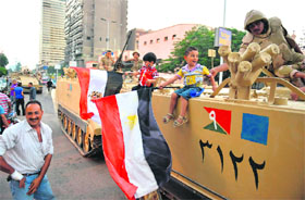 Egyptian children hold national flags as they pose for pictures near army soldiers on an armoured personnel carrier (APC) in a Cairo street on July 3, 2013 after the Egyptian army deployed dozens of armoured vehicles near a gathering of Islamist President Mohamed Morsi's supporters.