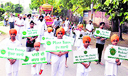 Children holding placards having messages on saving environment take part in a green nagar kirtan, organised by the EcoAmritsar, to commemorate the foundation day of Amritsar on Friday