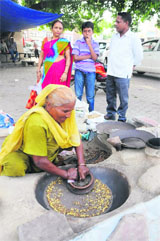 Eking out a living: An old woman roasts cereals alongside the Amrik Singh road in Bathinda on Friday.