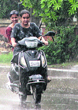 Girls enjoy a ride on a scooter during rain in Jalandhar.