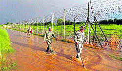 BSF jawans patrol the flooded fence along the border in Jammu on Saturday