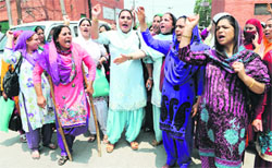 Anganwadi workers and helpers shout slogans in support of their demands during a protest in Srinagar on Saturday.