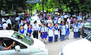 A traffic marshal guides children through traffic after the closing hours at Government Girls Model Senior Secondary School, Sector 18, in Chandigarh.