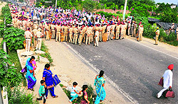 Policemen try to stop teachers during a protest near the Jalandhar bypass in Ludhiana on Sunday; and (right) commuters prefer to walk to reach their destination following a traffic jam