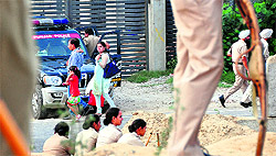 Policemen try to stop teachers during a protest near the Jalandhar bypass in Ludhiana on Sunday; and (right) commuters prefer to walk to reach their destination following a traffic jam