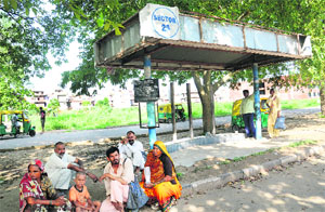 Commuters sit on the pavement as they wait for the bus at a CTU bus stop in Sector 25. The chairs at the stop had reportedly been stolen around six months ago. 