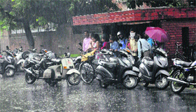 Commuters take shelter at a bus stop as the rain hit the city on Monday morning.