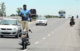 Daredevil: Putting his and other commuters lives at risk, a biker stands atop his Bullet motorycle as he crosses a bridge near Phagwara on Monday