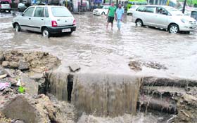 Death trap: Commuters wade through a badly damaged waterlogged road in Patiala on Monday