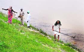 Workers remove trash from Sukhna Lake in Chandigarh on Tuesday