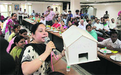 Congress councillor Aruna Arora shows a model of Mayor house while protesting against the sale of properties by the Municipal Corporation during the House meeting in Jalandhar on Tuesday.