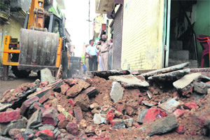 An earth-moving machine removes encroachments during a demolition drive at the Ambedkar Colony in Ludhiana on Tuesday
