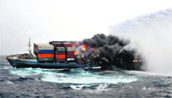 A section of the derelift MV Mol Comfort burns as the Indian Coast Guard ship Samudra Prahari lays down a column of water to extinguish the flames.  AFP 