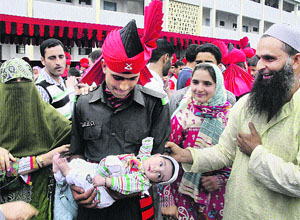An Army recruit, Ishfaq Ahmad, holds his six-month-old son after the Attestation-cum-Passing out Parade at the Jammu and Kashmir Light Infantry Headquarters in Srinagar on Wednesday.