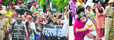 Anaganwari workers hold a protest in Ludhiana on Wednesday; and (right) a harassed parent carries his child.
