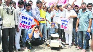 Activists of the Youth Congress burn an effigy of a BMW car in Jagraon on Wednesday to protest against the state government. 