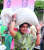 A beneficiary carries a sack of rice received by her under the Anna Bhagya scheme at Chikmagalur in Karnataka on Wednesday. 