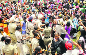 Police personnel try to control protesting anganwari workers and helpers outside the district administrative complex in Sangrur on Wednesday