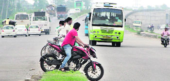 A motoryclist and some cyclists risk their lives by crossing a divider on the busy Jalandhar-Amritsar national highway. Photo: Sarabjit Singh