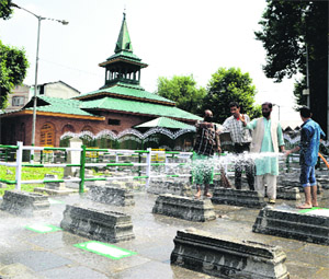 Srinagar Municipal Corporation employees clean graves at Mazar-e-Shohda at Khanyar Downtown in Srinagar on Friday. 