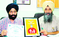 Senior Medical Officer Balbir Singh Dhillon (left) and SMO Ranjit Singh Buttar show the state-level award to mediapersons in Amritsar on Saturday. Photo: Sameer Sehgal