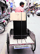 A man ferries a refrigerator on a cart bearing a number plate at Dhobi Bazaar in Bathinda on Sunday