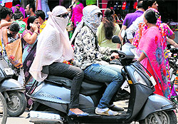 Girls travel on a scooty with their faces covered to protect themselves from the sultry weather in Bathinda on Sunday