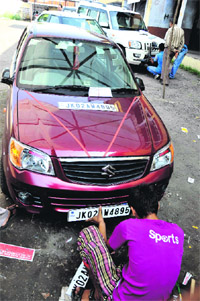 A worker is busy fixing a high security number plate on a car at the old RTO office in Jammu. 