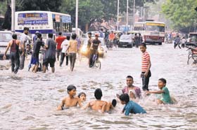 Out for a swim: Boys play on a waterlogged road after a heavy rain in Jaipur on Sunday