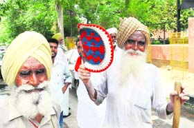 Sizzling summer: An elderly man uses a hand fan outside the District Administrative Complex during a demonstration in Bathinda on Monday