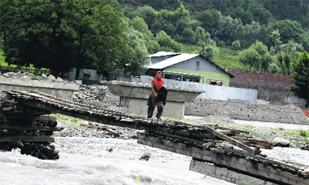 A woman walks over a wooden bridge in Kangan near Sonamarg in Ganderbal district. 