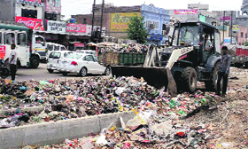 An earth-moving machine lifts garbage in Khanna on Monday.
