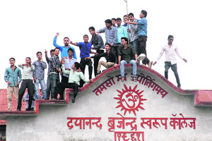 Students of DBS (PG) College climb up the roof of the college building in support of their demands in Dehradun on Tuesday.