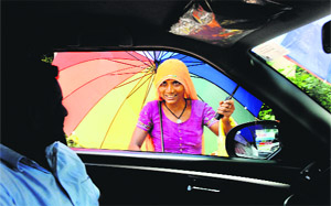 A Rajasthani woman persuades a prospective customer to buy umbrellas on the BC road in Jammu. 