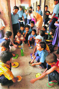 Children eat mid-day meal at a government school in Patna on Wednesday.