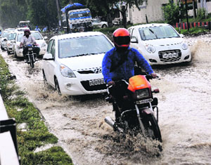 Commuters make way through the waterlogged national highway in Kharar on Thursday.
