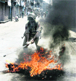A policeman removes a burning tyre from a street during a clash with protesters in Srinagar on Thursday.  PTI