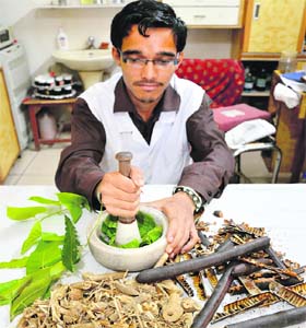 A pharmacist crushing herbs at an ayurveda clinic in Ludhiana