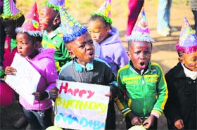 Children hold placards to greet Nelson Mandela on his birthday outside the Medi-Clinic Heart Hospital in Pretoria on Thursday